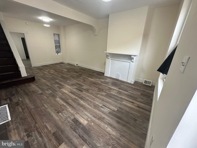 basement with stairs, dark wood-type flooring, baseboards, and visible vents