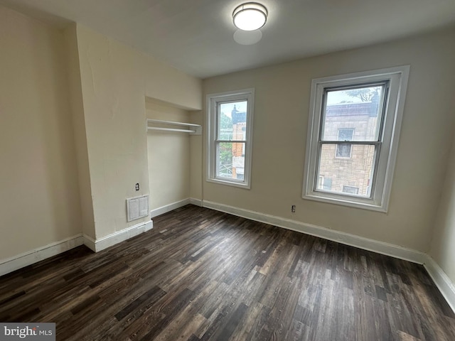 unfurnished room featuring dark wood-type flooring, baseboards, and visible vents