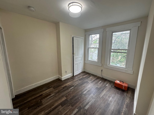 unfurnished bedroom featuring dark wood-type flooring, baseboards, and a closet