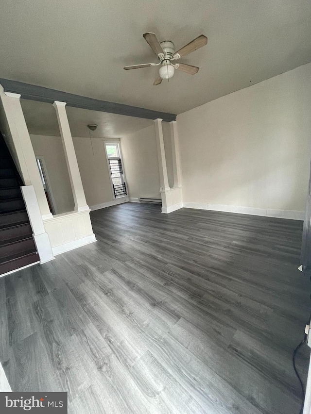 unfurnished living room featuring a baseboard heating unit, baseboards, stairs, a ceiling fan, and dark wood-style flooring