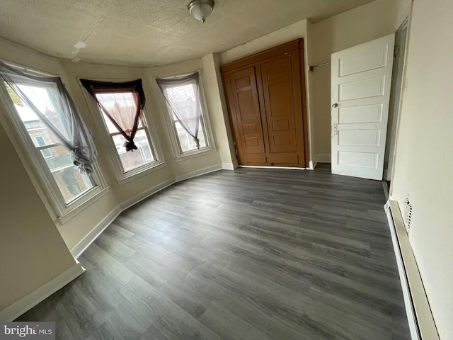 interior space featuring dark wood finished floors, baseboards, and baseboard heating