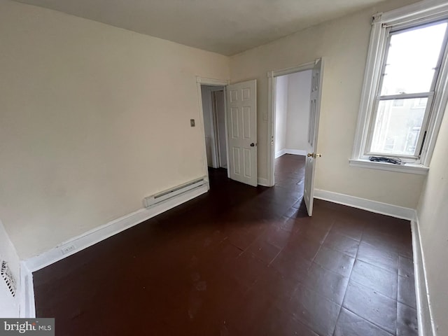 unfurnished room with a baseboard heating unit and baseboards