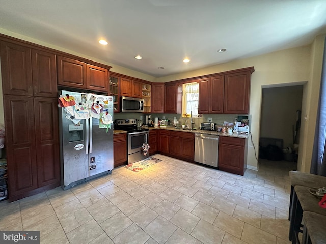 kitchen featuring light stone countertops, appliances with stainless steel finishes, and sink