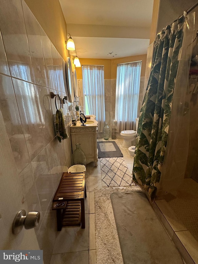 bathroom with tile walls, a bidet, a shower with shower curtain, vanity, and toilet