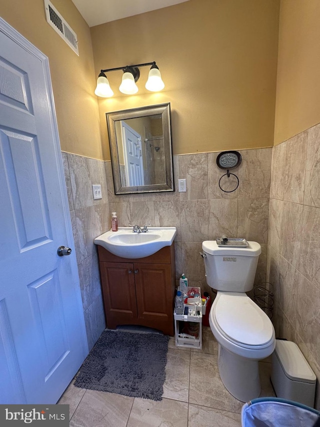 bathroom with tile walls, tile patterned flooring, vanity, and toilet