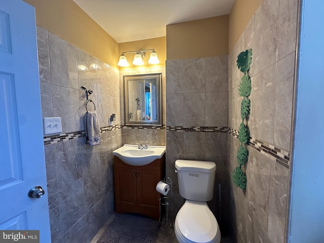 bathroom with tile walls, vanity, and toilet