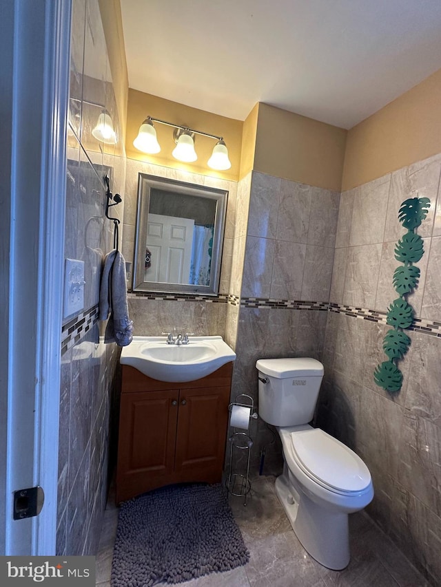 bathroom featuring vanity, tile walls, tile patterned flooring, and toilet