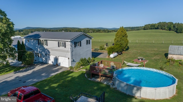 view of swimming pool with a rural view, a wooden deck, and a lawn