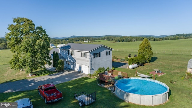 view of swimming pool with a lawn and a rural view