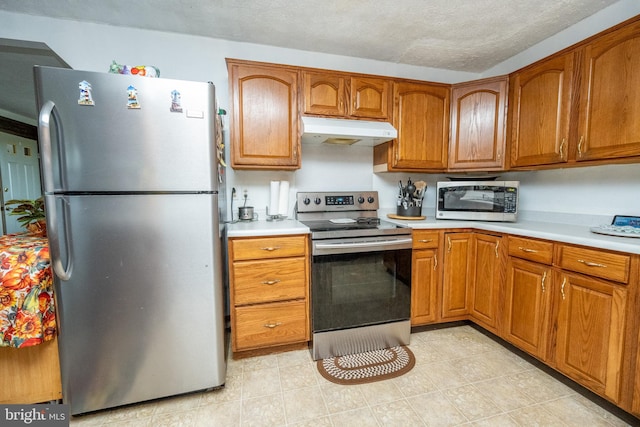 kitchen with a textured ceiling, stainless steel appliances, and light tile patterned floors