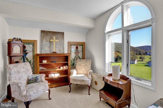 sitting room featuring a mountain view, beamed ceiling, and carpet flooring