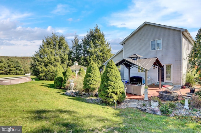 rear view of property with a yard, a patio area, a gazebo, and an outdoor fire pit