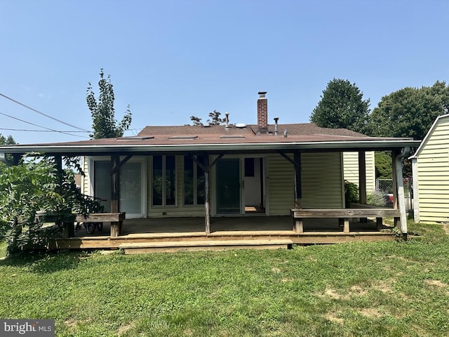 rear view of property featuring a yard, a wooden deck, and a chimney