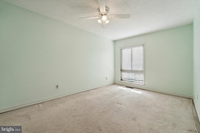 carpeted empty room with ceiling fan and a textured ceiling