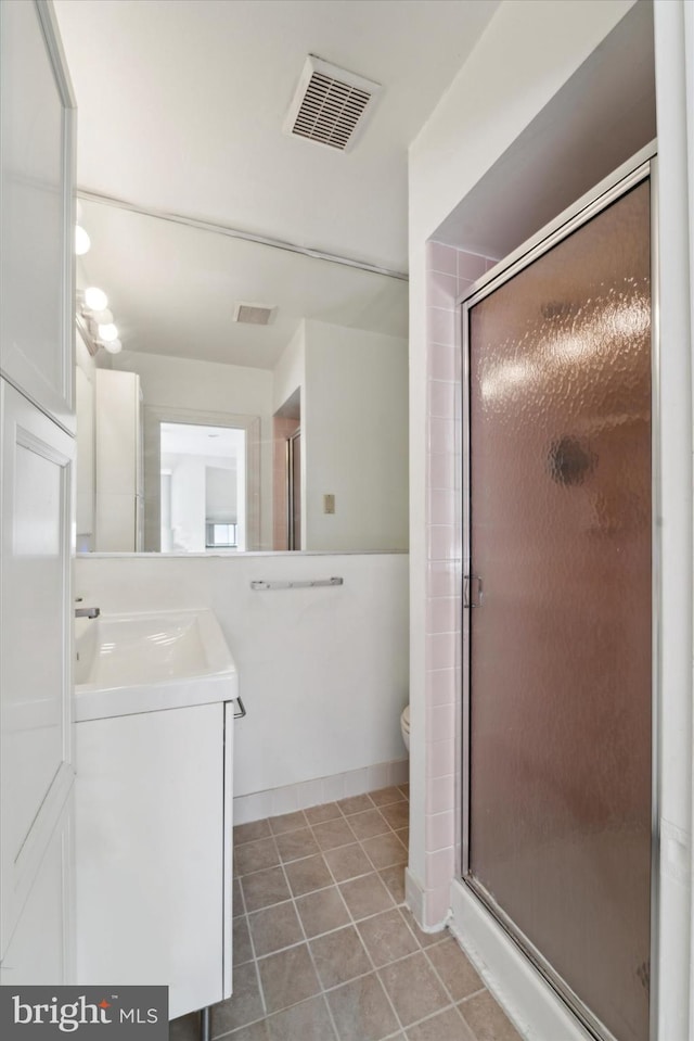 bathroom featuring walk in shower, vanity, toilet, and tile patterned floors