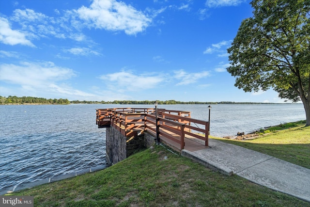 view of dock with a yard and a water view