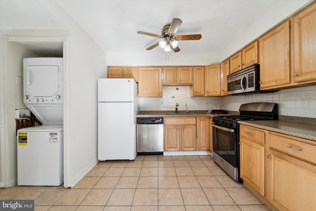 kitchen with ceiling fan, sink, stainless steel appliances, stacked washer and dryer, and decorative backsplash