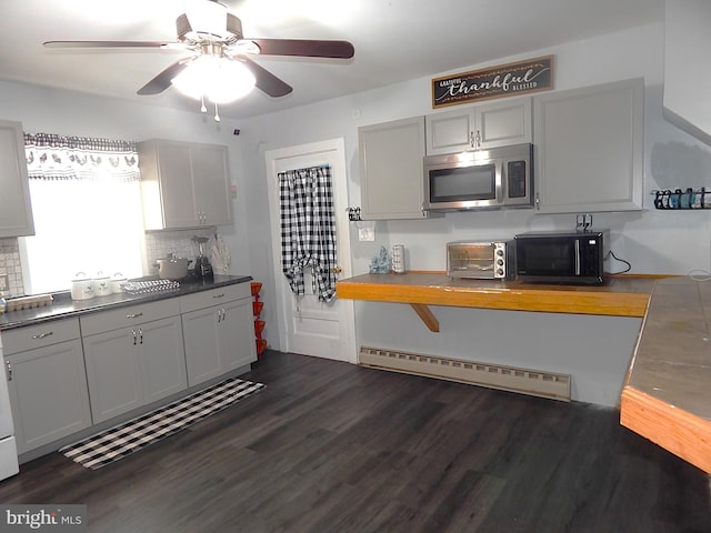 kitchen with stainless steel microwave, a toaster, dark wood-type flooring, and a baseboard radiator