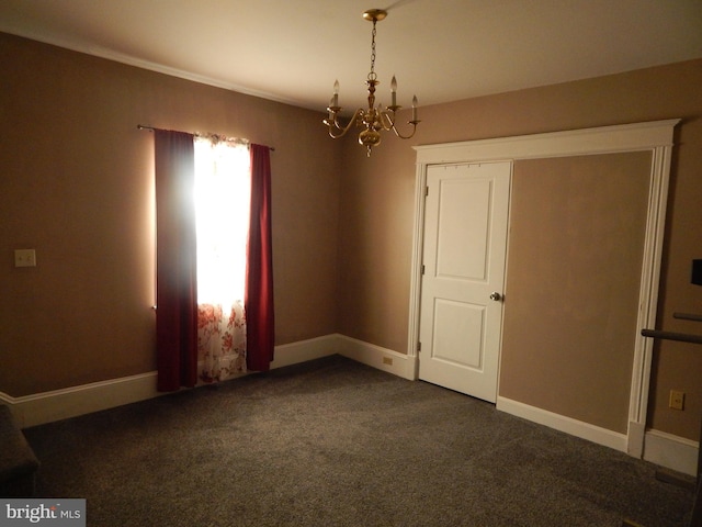 unfurnished room with dark colored carpet, baseboards, and an inviting chandelier