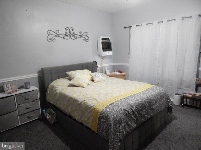 bedroom with heating unit, wainscoting, and dark carpet