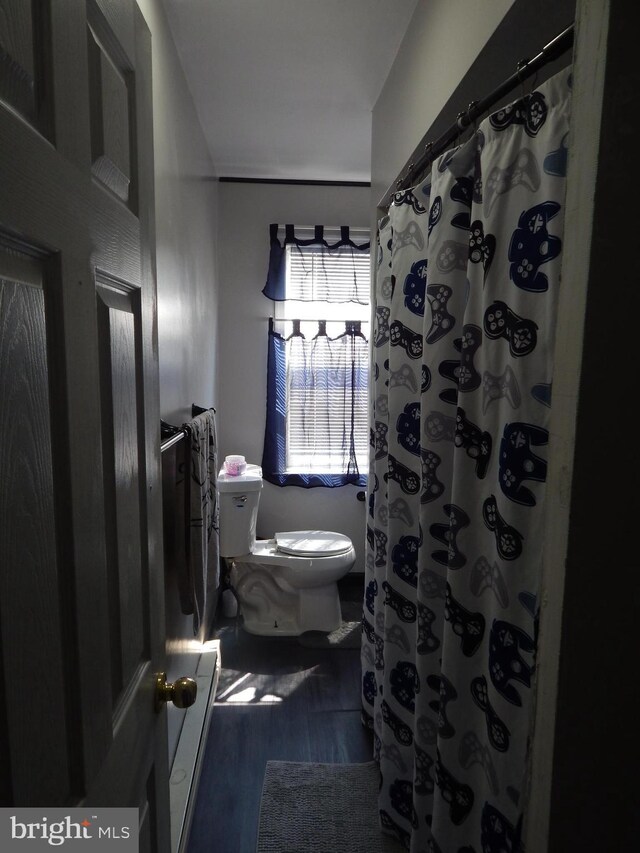 bathroom with a shower with curtain, toilet, and wood finished floors