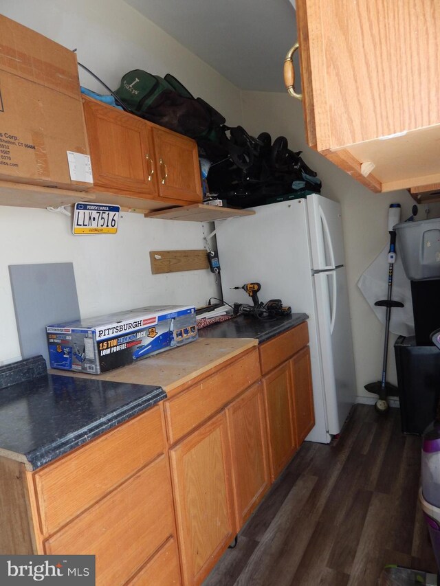 kitchen with dark wood-style floors, dark countertops, and freestanding refrigerator