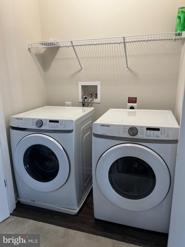 laundry area with washing machine and dryer and dark wood-type flooring