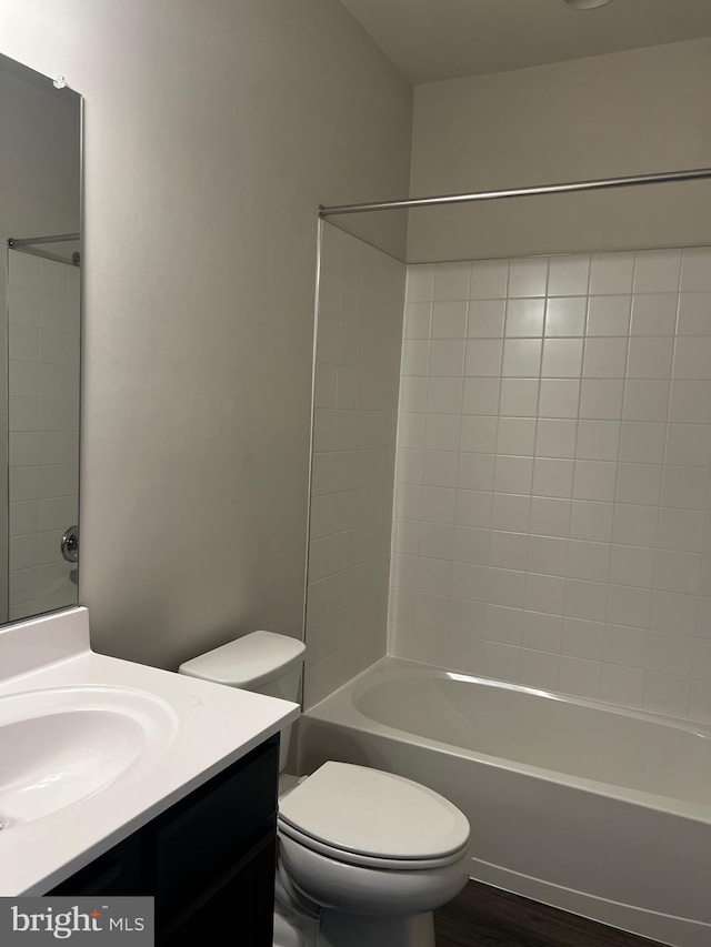 full bathroom with hardwood / wood-style flooring, tiled shower / bath combo, vanity, and toilet