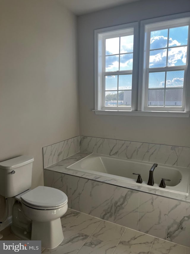 bathroom featuring tiled bath and toilet