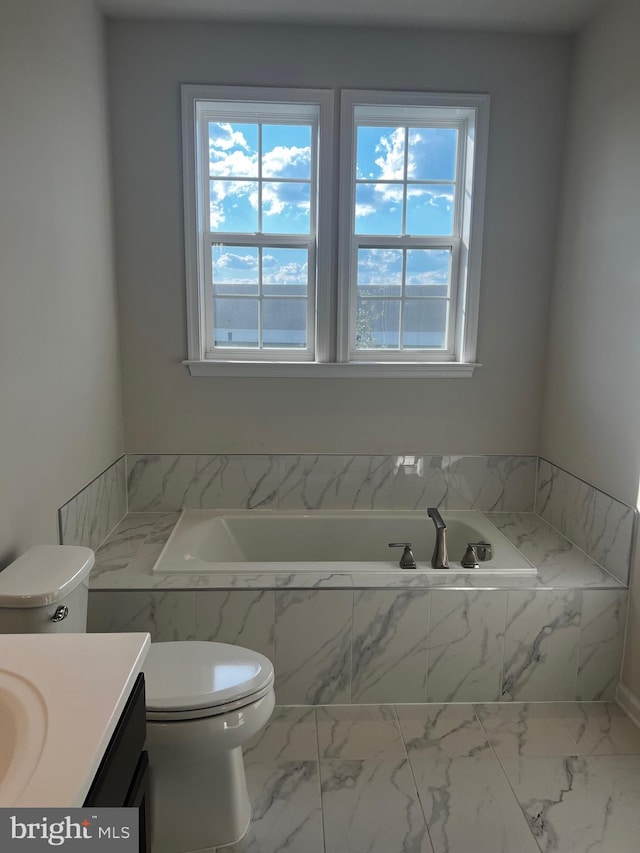 bathroom featuring vanity, tiled bath, and toilet