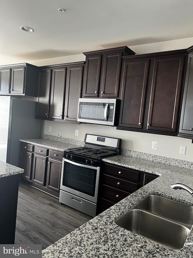 kitchen featuring dark brown cabinetry, stainless steel appliances, dark wood-type flooring, and sink