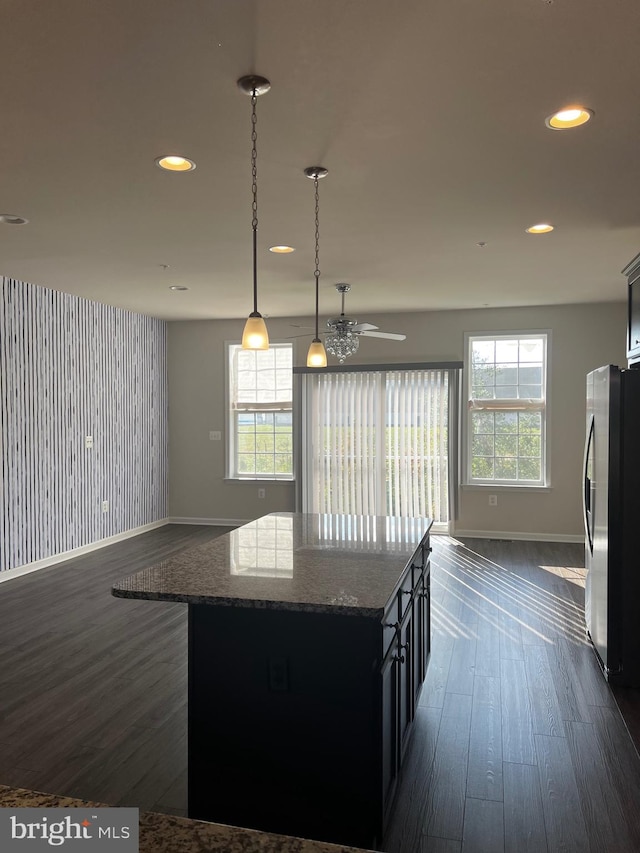 kitchen featuring decorative light fixtures, a center island, a healthy amount of sunlight, and stainless steel fridge