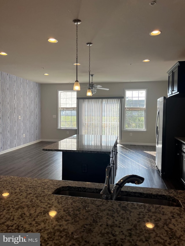 kitchen featuring ceiling fan, a kitchen island, a healthy amount of sunlight, and decorative light fixtures