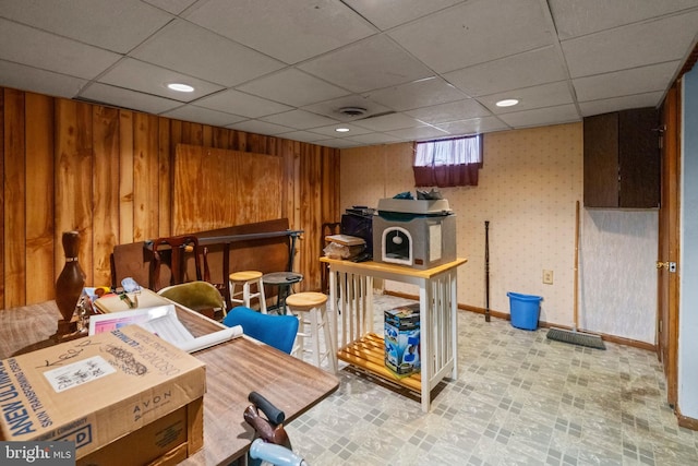 interior space with a paneled ceiling and wooden walls