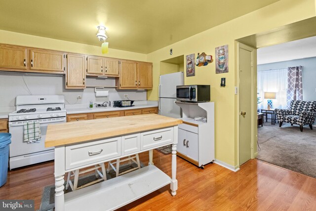 kitchen with white cabinets, white appliances, light hardwood / wood-style floors, and wood counters