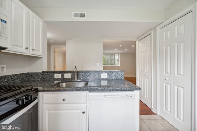 kitchen with white appliances, light hardwood / wood-style floors, sink, white cabinetry, and dark stone counters