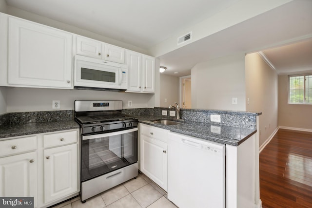 kitchen featuring white appliances, light hardwood / wood-style flooring, sink, dark stone countertops, and white cabinets