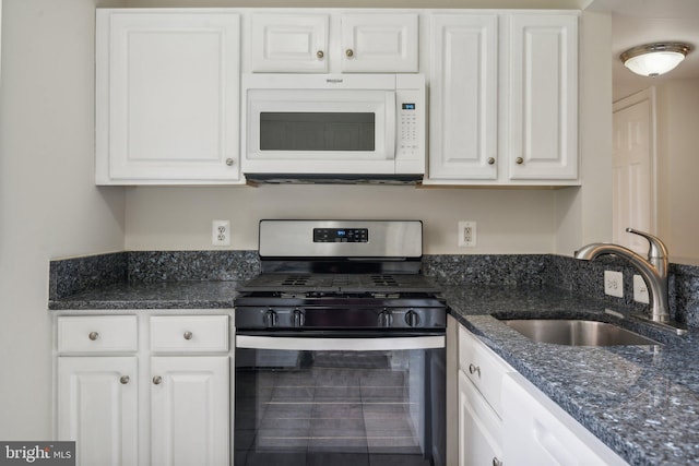 kitchen featuring dark stone countertops, stainless steel range with gas cooktop, sink, and white cabinets