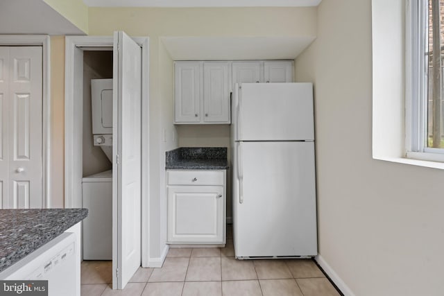 kitchen featuring white cabinetry, light tile patterned floors, white appliances, and stacked washer / drying machine