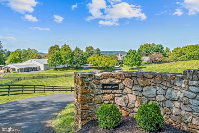 community / neighborhood sign with a rural view and a lawn