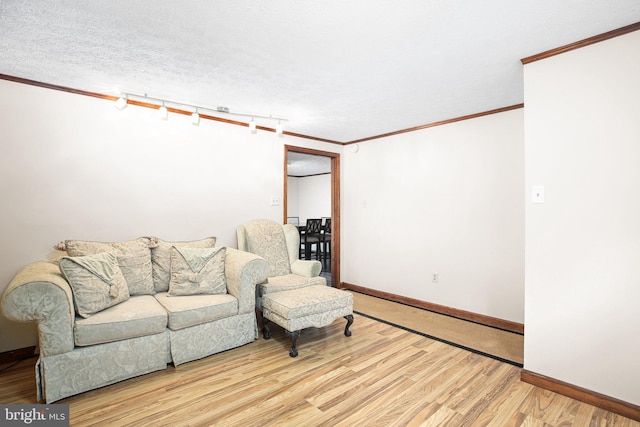 living room featuring light wood-type flooring, rail lighting, a textured ceiling, and ornamental molding