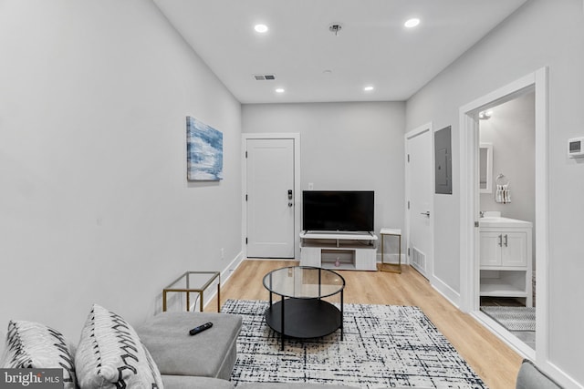 living room featuring light wood-type flooring, electric panel, and sink