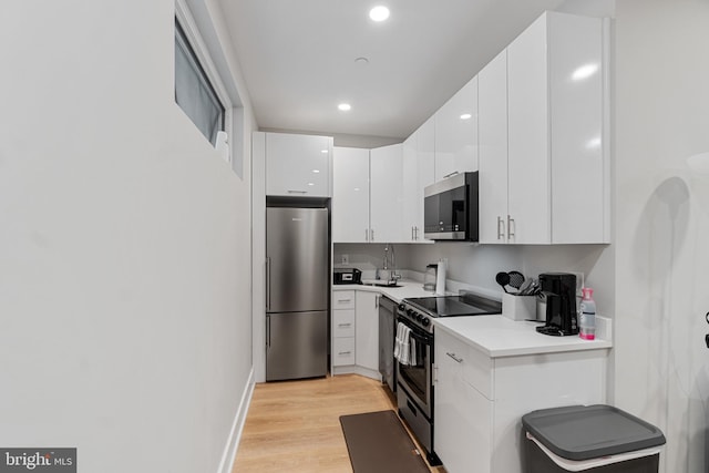 kitchen featuring sink, appliances with stainless steel finishes, white cabinets, and light hardwood / wood-style floors