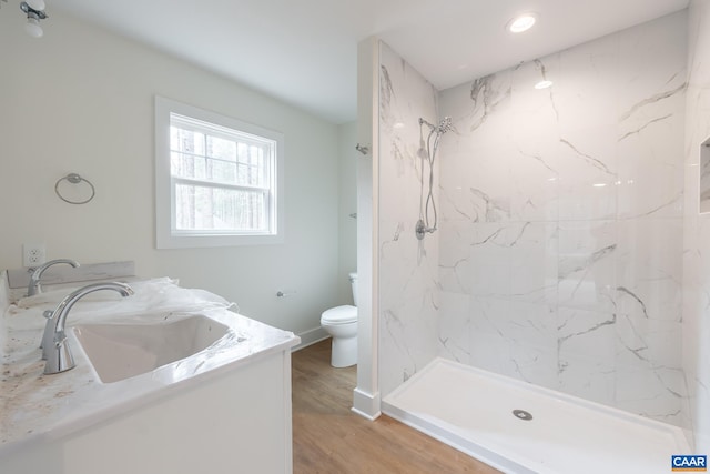 bathroom with a marble finish shower, vanity, toilet, and wood finished floors