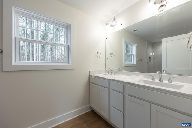 bathroom with baseboards, walk in shower, a sink, and wood finished floors