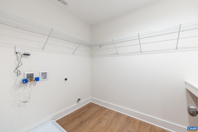 clothes washing area featuring laundry area, baseboards, hookup for a washing machine, hookup for an electric dryer, and light wood-type flooring