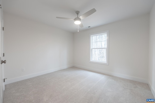 empty room with a ceiling fan, light colored carpet, and baseboards