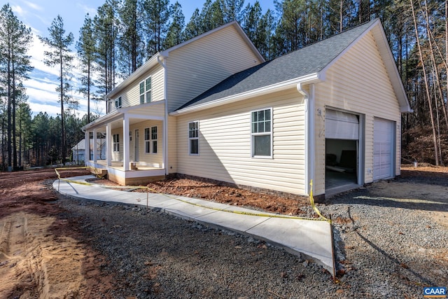 view of home's exterior featuring a porch, roof with shingles, and an attached garage