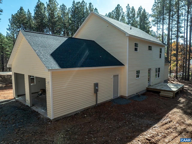 rear view of house featuring a shingled roof