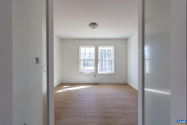 empty room featuring visible vents, baseboards, and wood finished floors